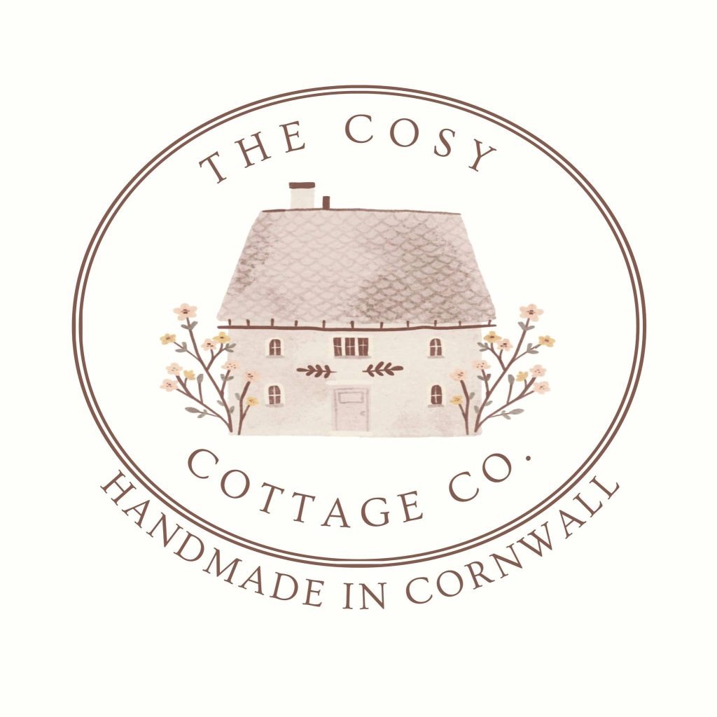 Logo of the Cosy Cottage Co in pink and beige with a small cottage and handmade in Cornwall written on it