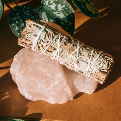 White sage bundle resting on a large rose quartz crystal.