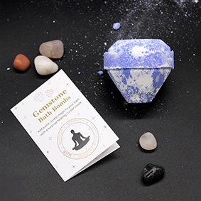 blue and white gemstone shaped bath bomb  on a black background with a list of crystals and their properties.