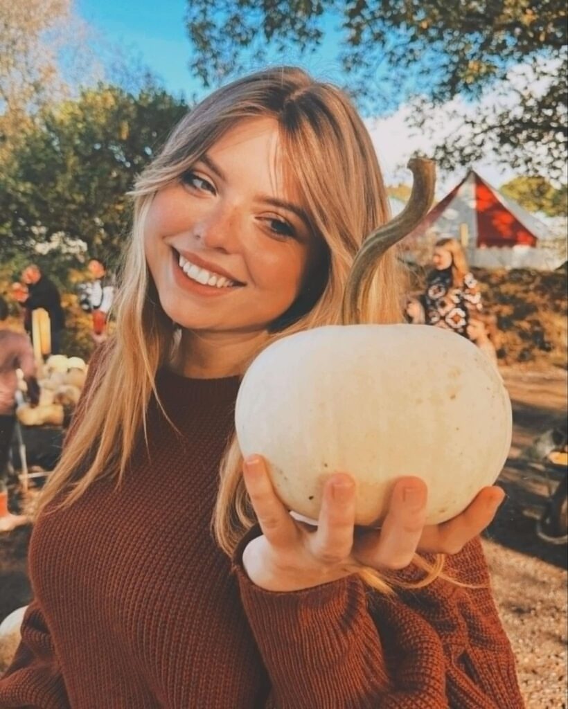 Photograph of young woman holding a pumpkin. The woman is Molly Down.